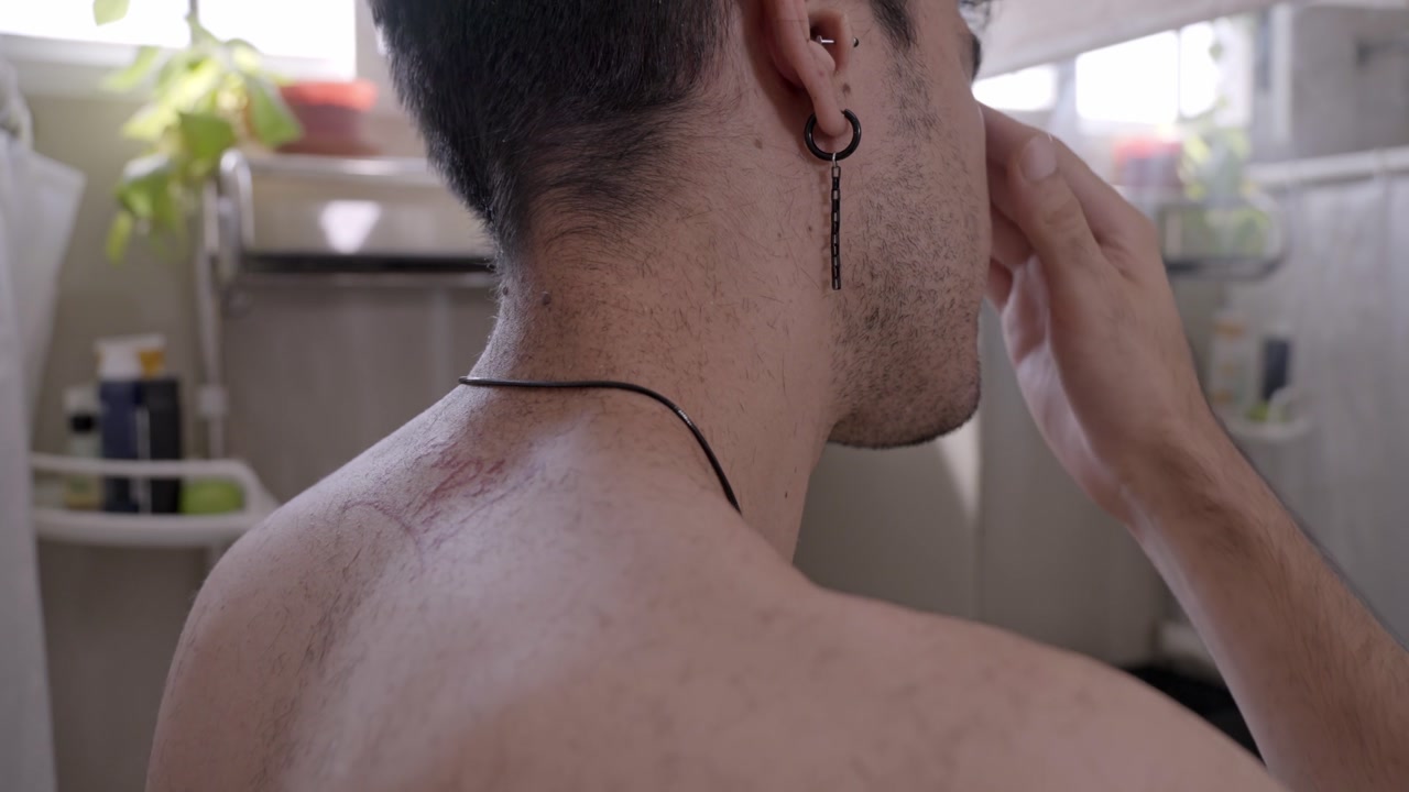 Professional tattooist carefully applying analgesic cream to a young client's neck, preparing the skin for a new tattoo in the studio