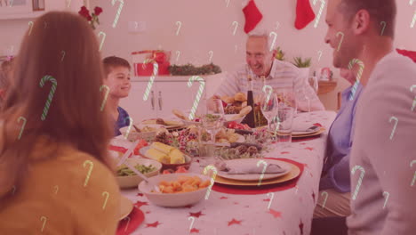 animación de bastones de caramelo cayendo sobre una familia caucásica sonriente cenando