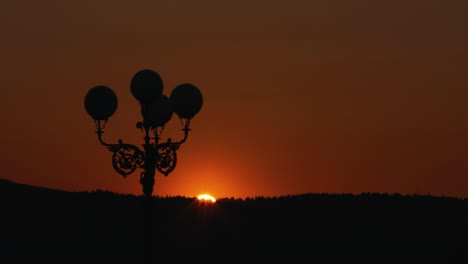Silhouette-Eines-Laternenpfahls-Bei-Sonnenuntergang-Mit-Orangefarbenem-Himmel