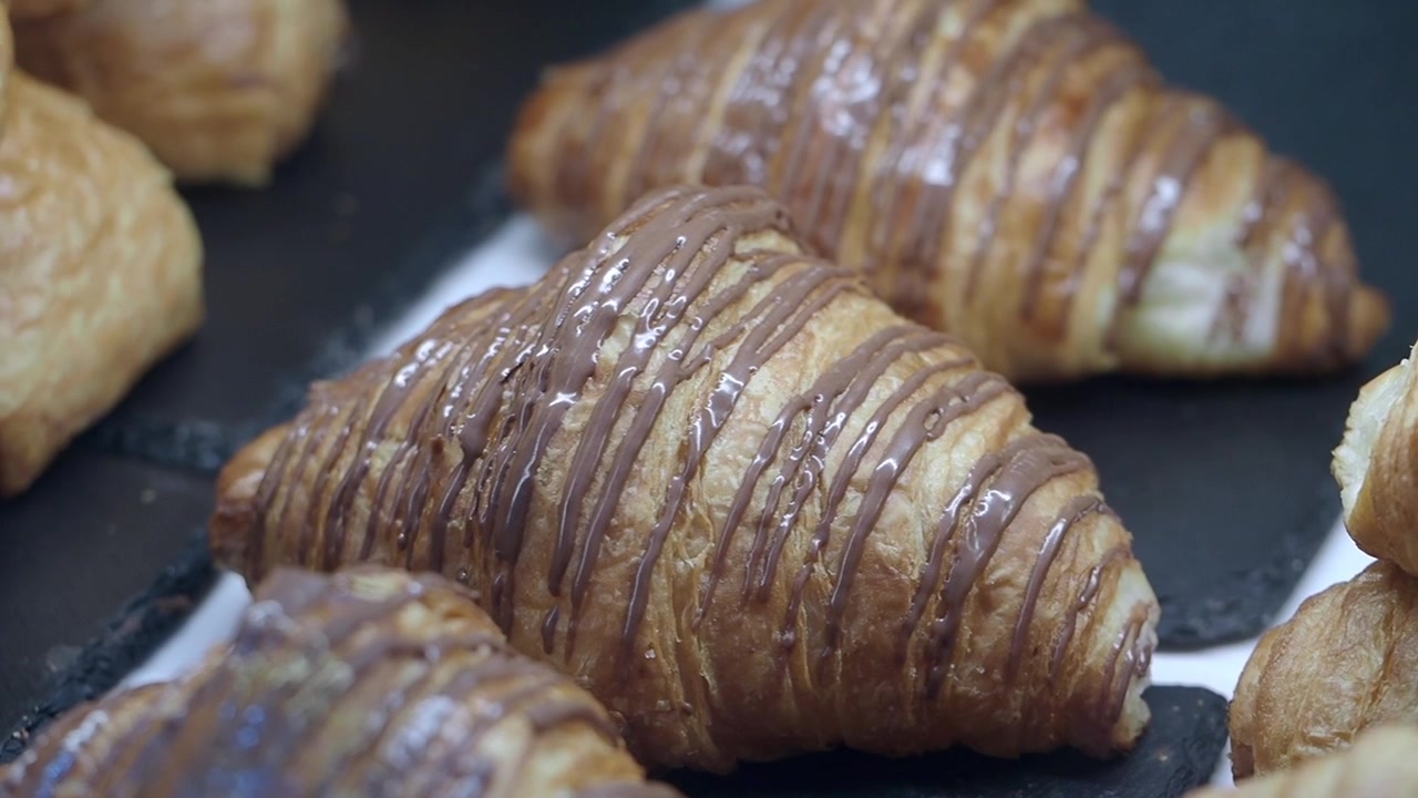 Cornetti appena sfornati ricoperti di cioccolato in vetrina di pasticceria