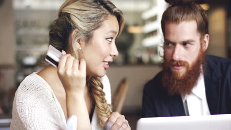 pareja joven haciendo compras en línea usando una tableta digital en una cafetería