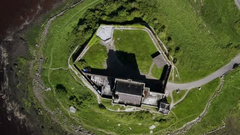 Vista-Aérea-Giratoria-De-Arriba-Hacia-Abajo-Del-Castillo-De-Dunguaire-Que-Muestra-Sus-Murallas-Y-El-Camino-Hacia-La-Torre