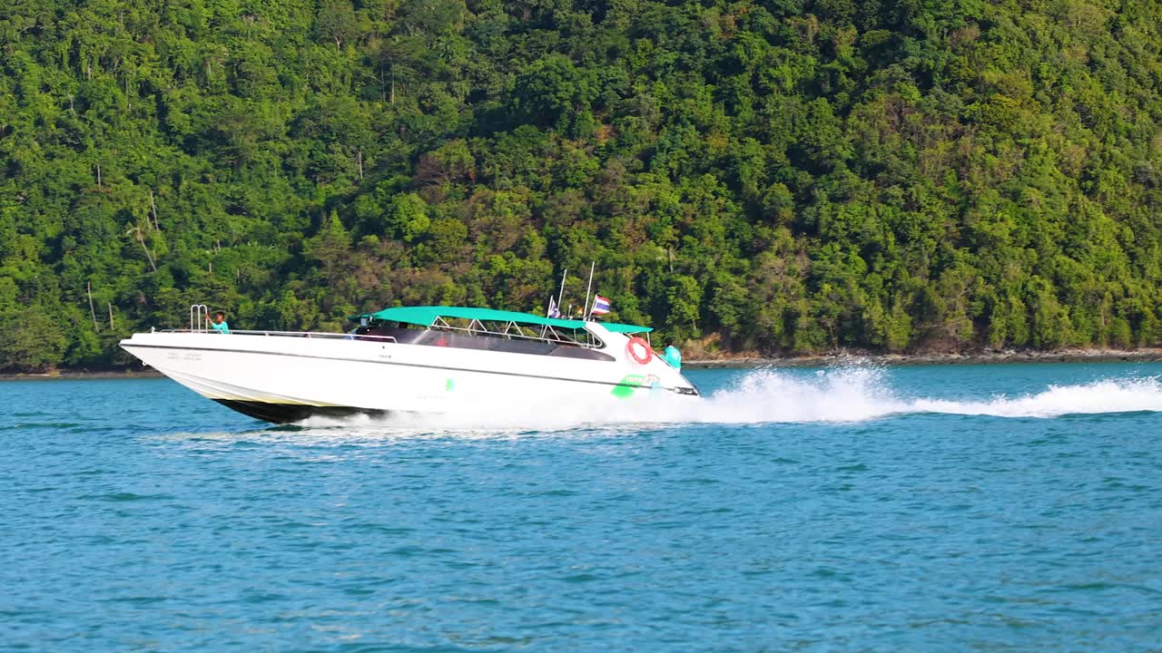 Un motoscafo scivola sulle acque blu di Phuket, circondato da lussureggianti colline verdi sotto la luce del giorno, catturando un senso di avventura.