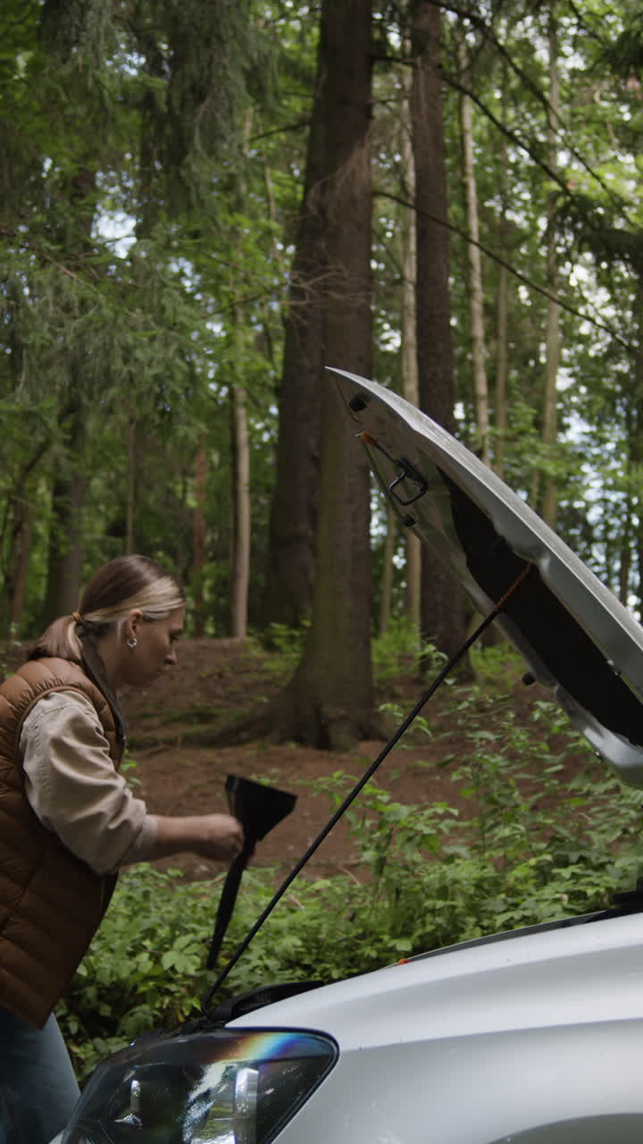 Woman troubleshooting car problem in the forest