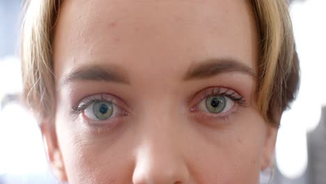 portrait close up of blue eyes of caucasian woman with bob and highlights smiling, in slow motion