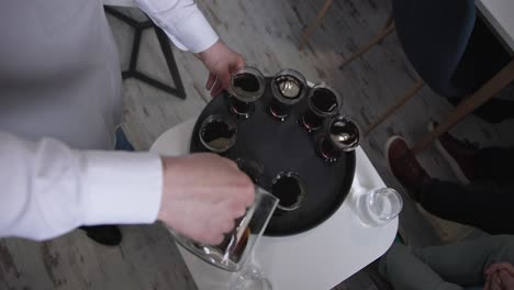 professional barista pours dark coffee into glass cups on spinning tray