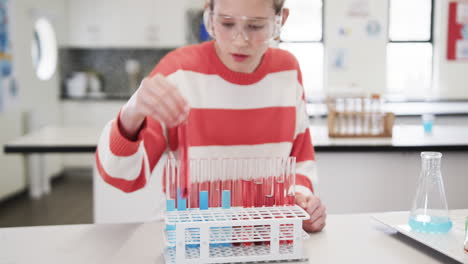 young girl in science class holding test tubes, excitedly conducting experiment, at school