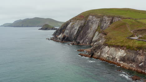 Entlang-Der-Küste-Fliegen.-Hoher-Und-Steiler-Felshang,-Der-Aus-Wasser-Aufsteigt,-Mit-Grünem-Gras-An-Der-Spitze.-Wunderschöne-Naturkulisse.-Irland