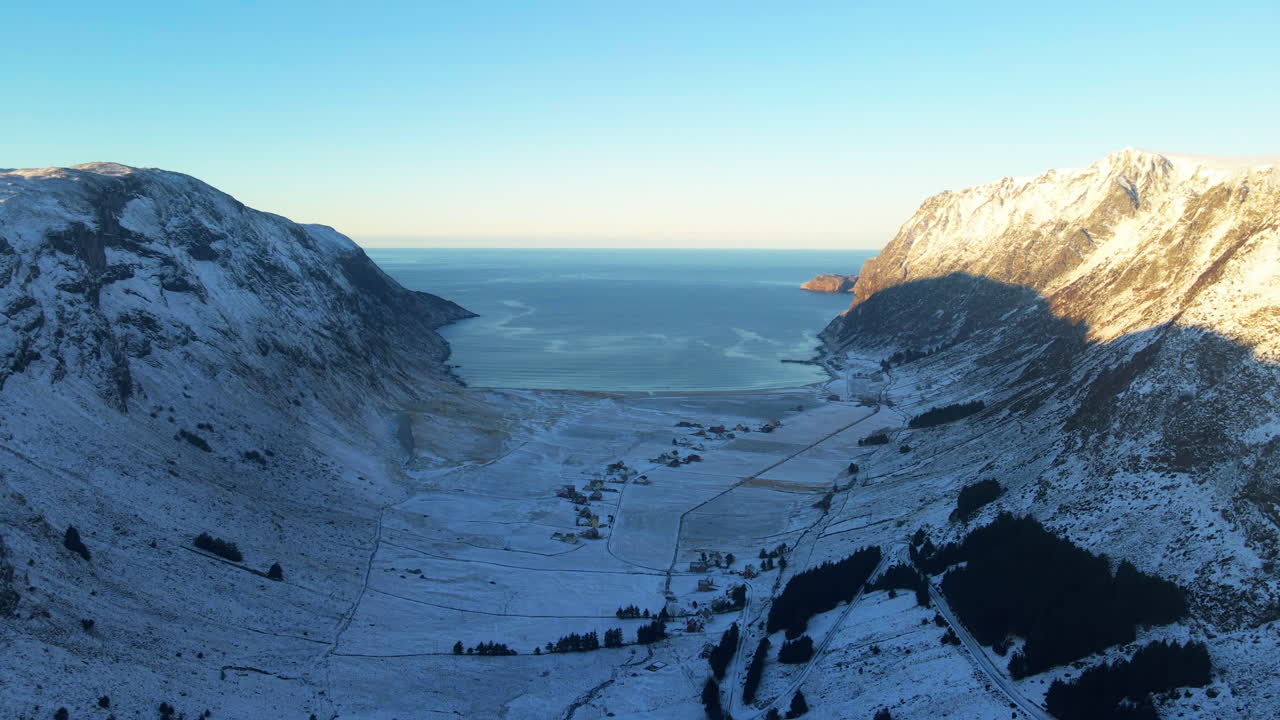 Naturskønt dronebillede over Hoddevik, et berømt surfsted på vestkysten af Norge, med udsigt til horisonten, hvor sne dækker landskabet og solen skinner på bjergene og