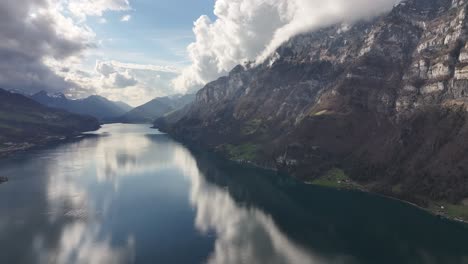 Pintorescas-Montañas-Que-Rodean-Un-Lago-Tranquilo,-Con-Cielo-Azul-Y-Nubes-Reflejadas-En-El-Agua