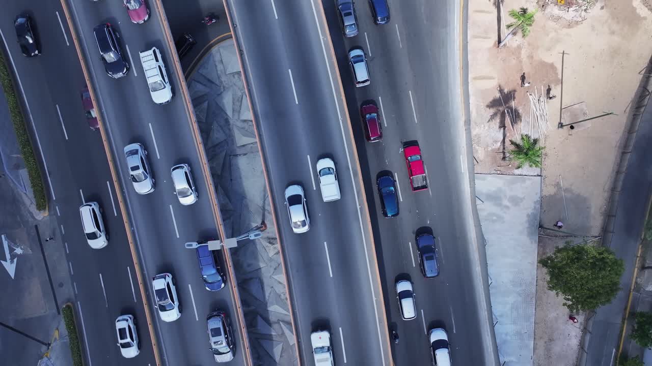 Overhead aerial shot of an avenue with moving vehicles in broad daylight, showcasing a well-lit urban landscape