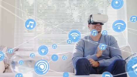 Animation-of-network-of-connections-with-icons-over-man-wearing-vr-headset