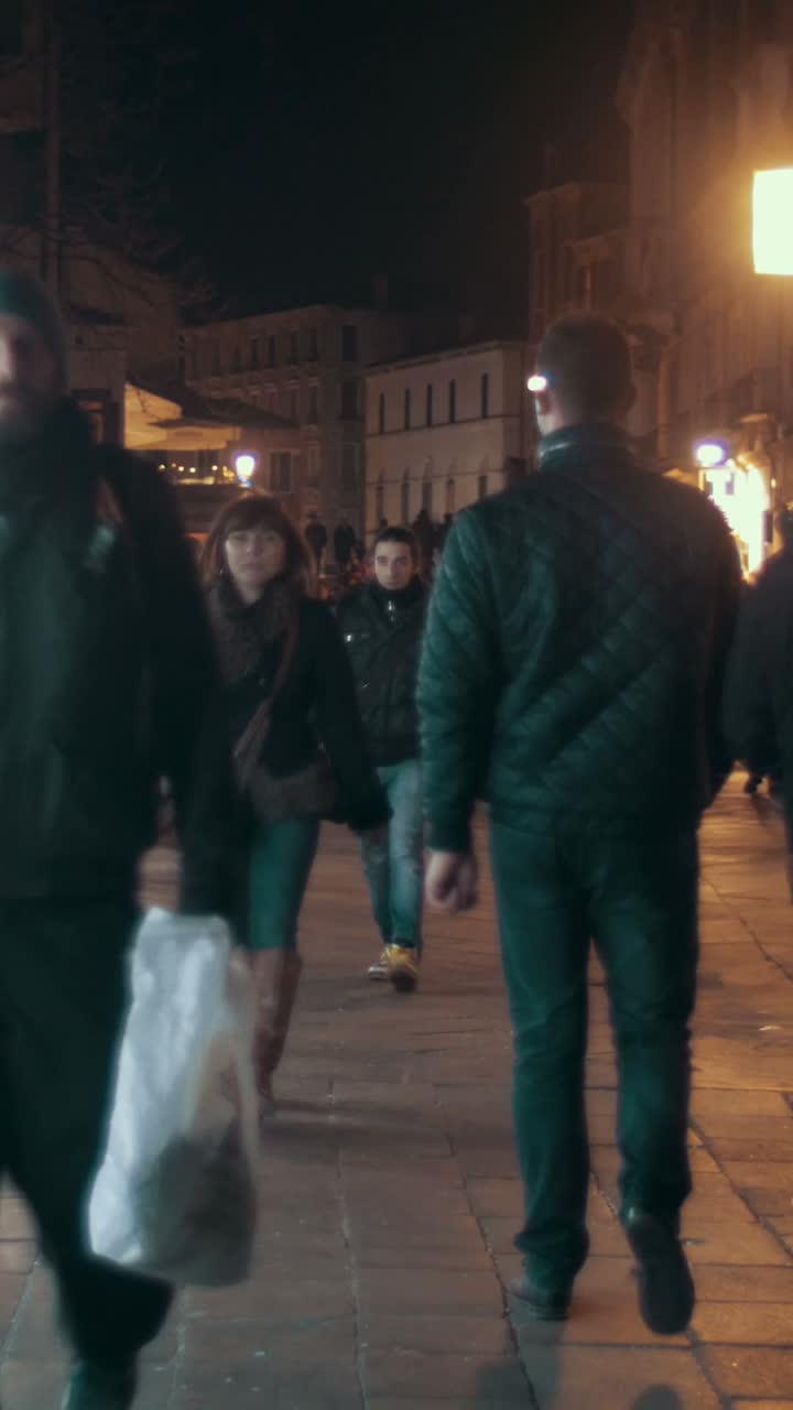 gente caminando por una calle de la ciudad por la noche
