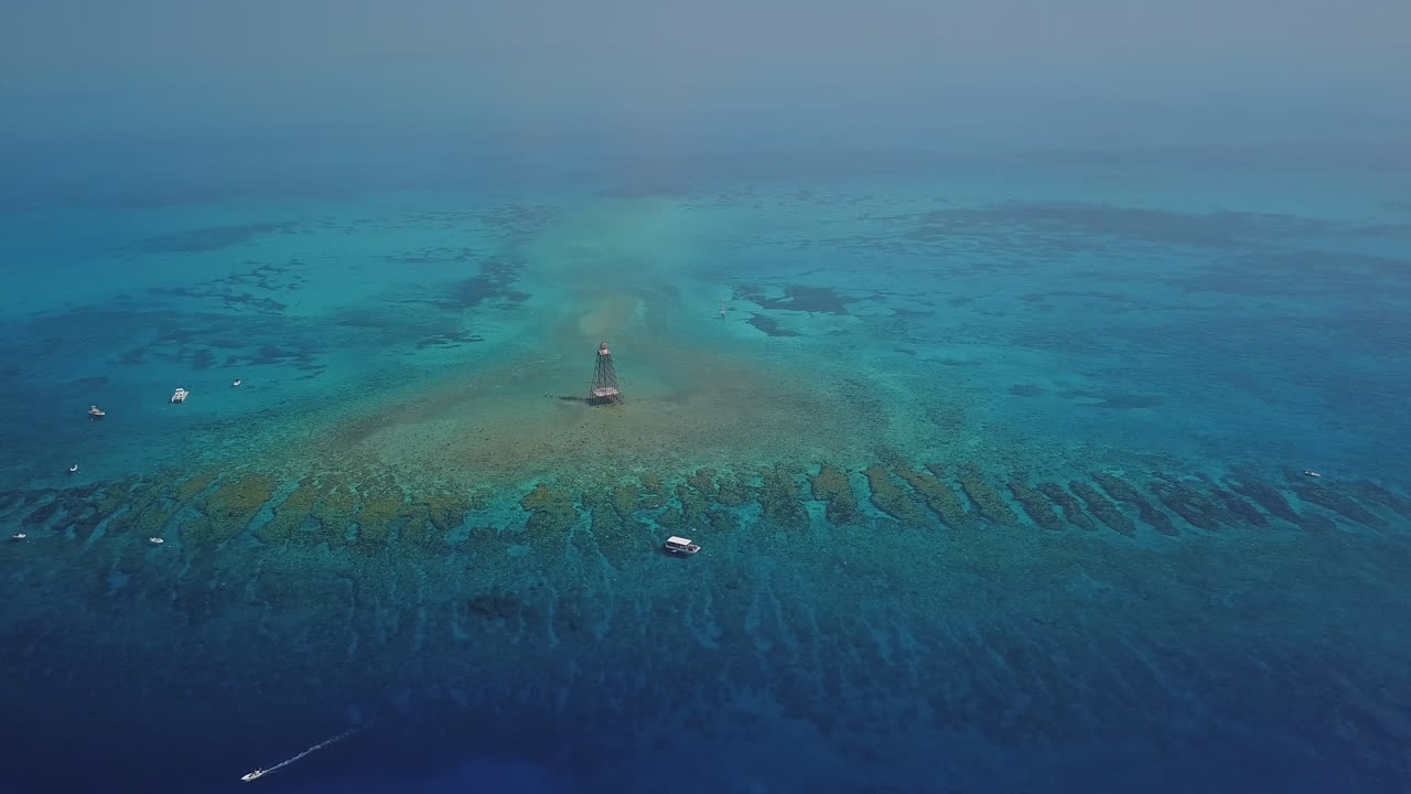Drone shot of Sand Key Lighthouse panning downward at high altitude