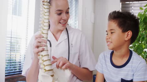 female physiotherapist explaining spine model to boy patient 4k