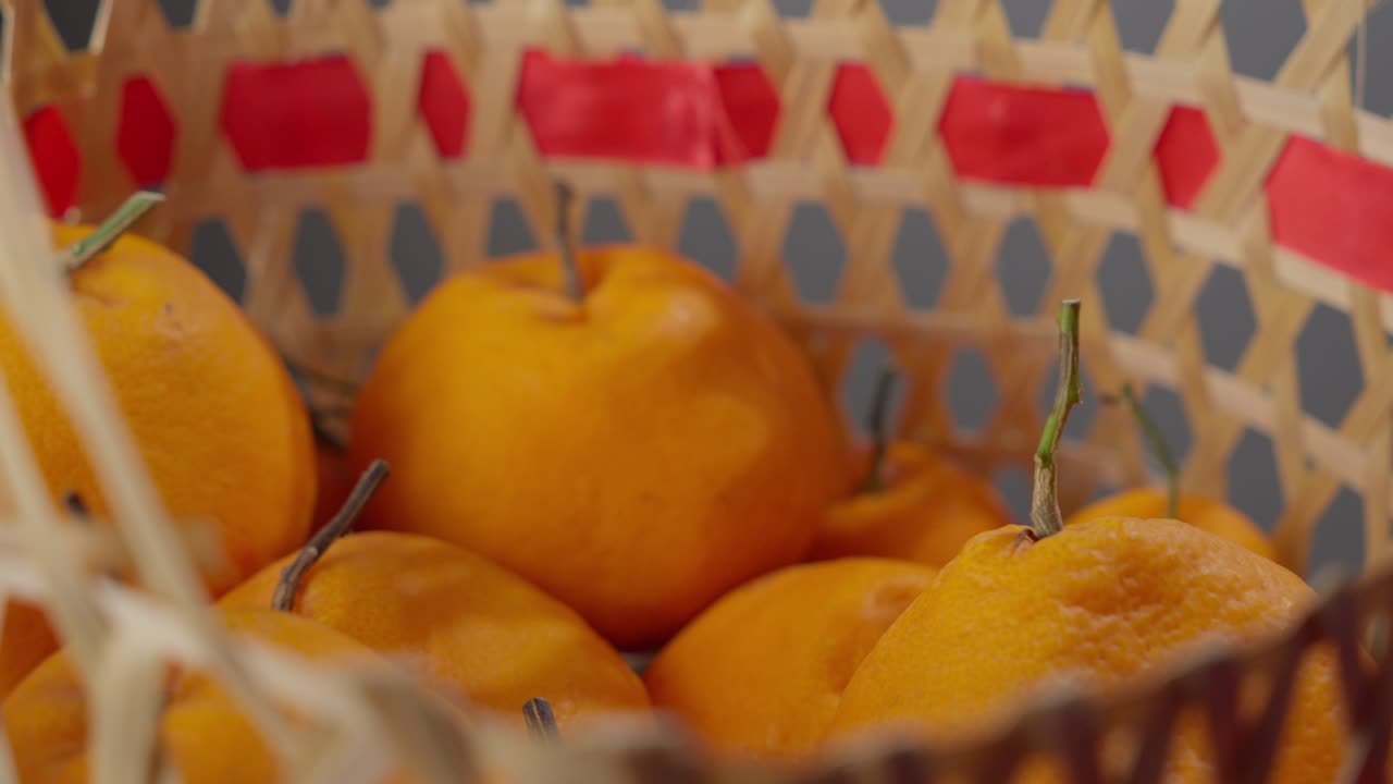la mano recogiendo una naranja madura de una canasta, detalle de color vibrante, primer plano