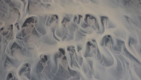 aerial top shot of glacial river pattern on iceland island during sunny day - rising top view