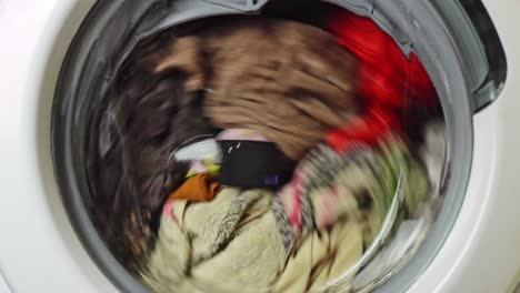 static view of clothes spinning in a washing machine door window and shaking inside the machine