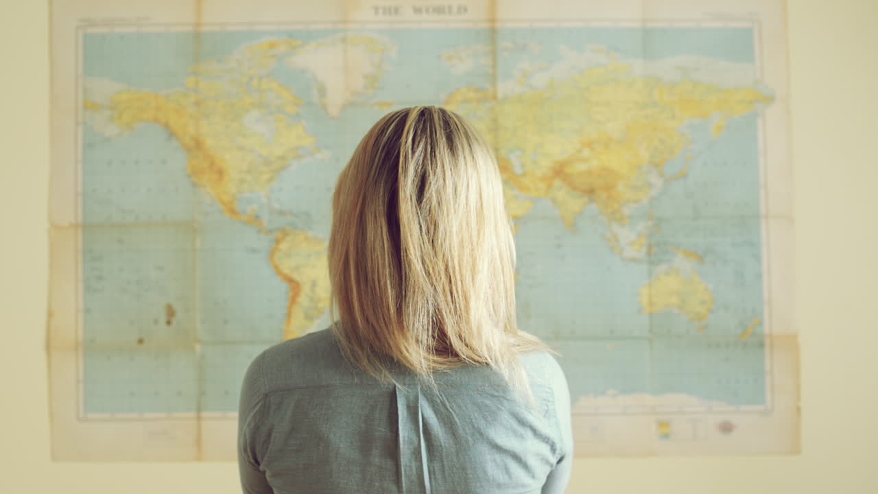 joven turista mujer de viaje mira el fondo del mapa del mundo