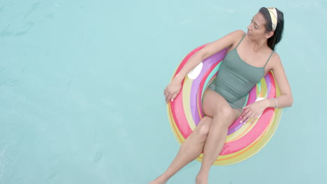 Young-biracial-woman-enjoys-a-relaxing-day-at-the-pool,-with-copy-space