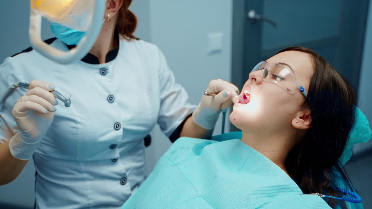 Patient sitting on dentist chair. Dentist in uniform perform dental operation on patient