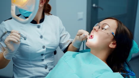 patient sitting on dentist chair. dentist in uniform perform dental operation on patient