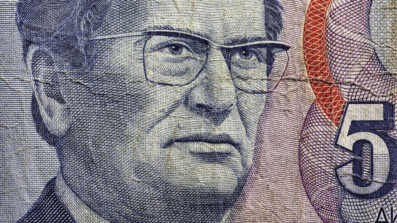 Close pan of worn Yugoslav 5000 dinar portrait with center crease and Cyrillic text
