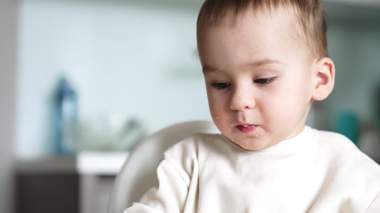 Lovely baby boy eating something. Adorable Caucasian kid with smudged face. Close up. Blurred backdrop.