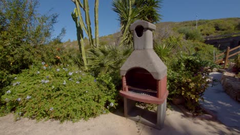 Stone-BBQ-grill-with-chimney-surrounded-by-green-vibrant-nature-of-Sardinia,-motion-view