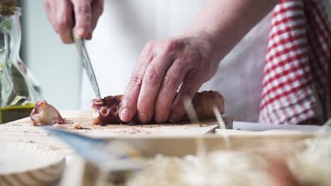primer plano de las manos de una persona cortando y preparando el pulpo