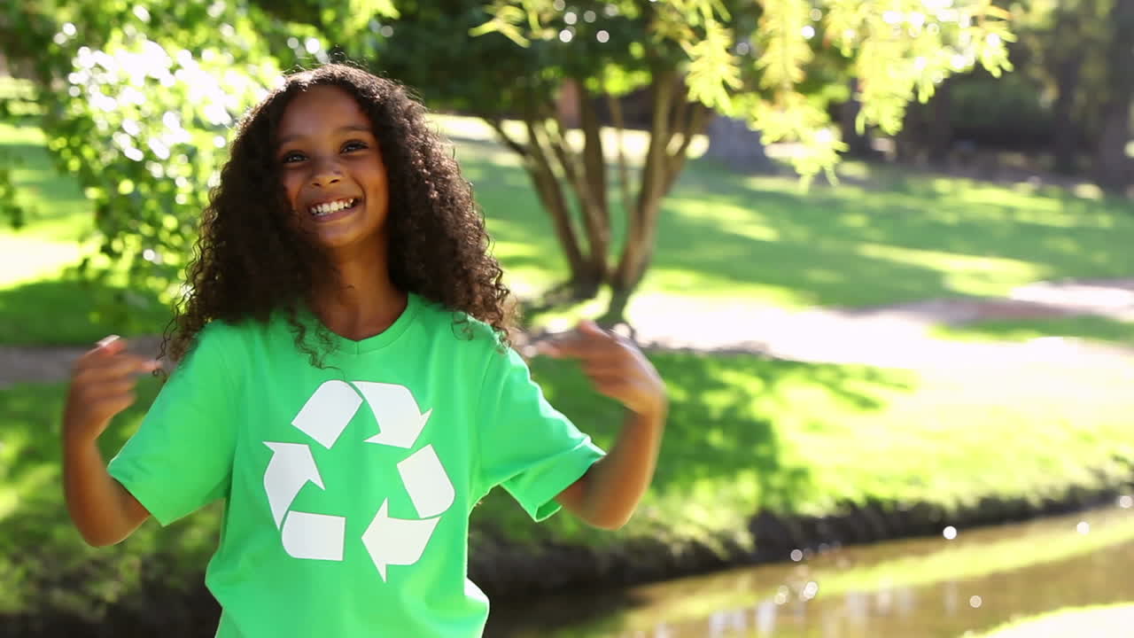 chica mostrando su camiseta de reciclaje en el parque