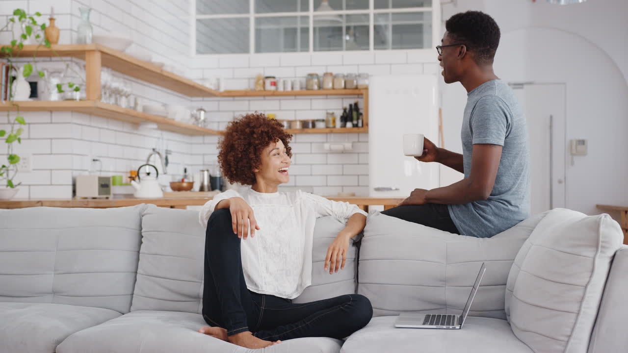 Young Couple Relaxing On Sofa At Home Together And Laughing