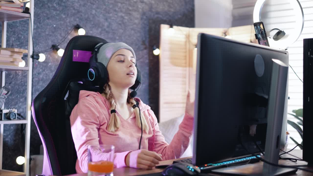una jugadora profesional de deportes electrónicos se quita los auriculares después de perder un videojuego en su computadora.