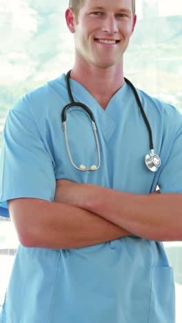 médico feliz mirando a la cámara con los brazos cruzados