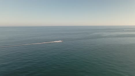 Vista-Aérea-Rápida-Siguiendo-El-Exceso-De-Velocidad-En-Una-Moto-De-Agua-A-Través-Del-Horizonte-Oceánico-Marino