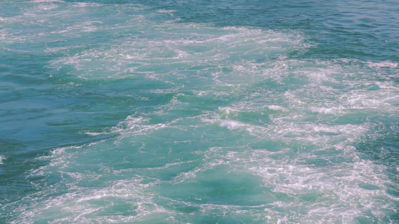 Vue du sillage hypnotique au ralenti d'un bateau, perturbant la mer calme, alors que les moteurs propulsent le navire vers l'avant 4K.