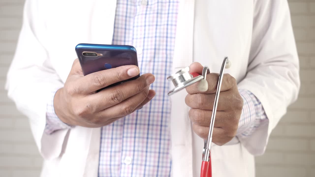 médico que utiliza teléfono inteligente y estetoscopio