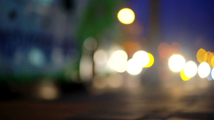 Cerchi bokeh colorati di semafori su strada cittadina notturna. Sfondo astratto
