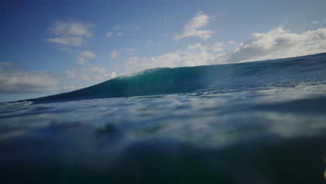 turquoise blue water at ocean surface as wave breaks into deep barrel