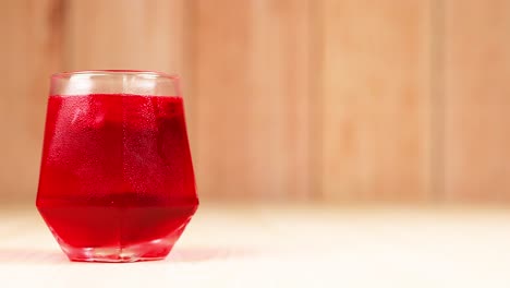 red drink in glass with wooden background