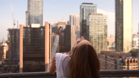 Selbstbewusste-Blonde-Weibliche-Geschäftsführerin,-Die-Auf-Einem-Balkon-Mit-Blick-Auf-Das-Stadtzentrum-Steht-Und-Sich-Umdreht-Und-In-Die-Kamera-Schaut