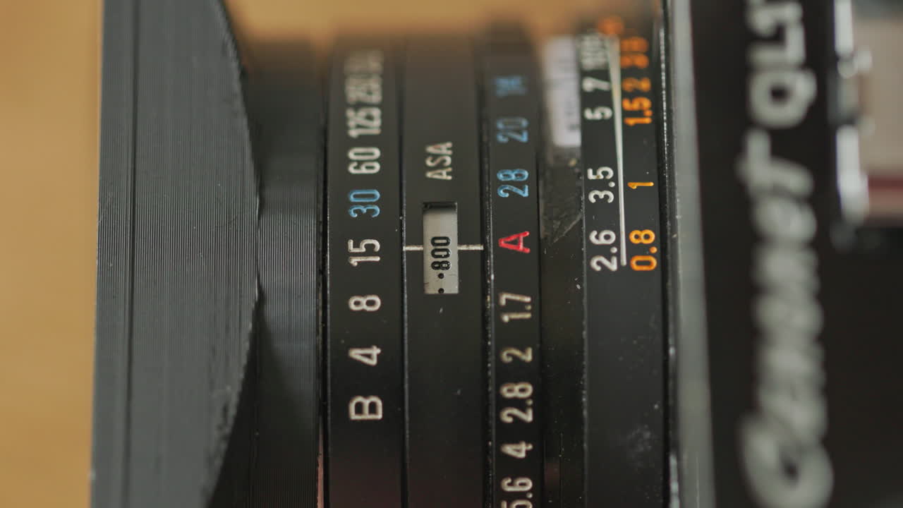 Static top shot of caucasian hands adjusting different settings on an old vintage film camera. Adjusting asa aputure and shutter speed.