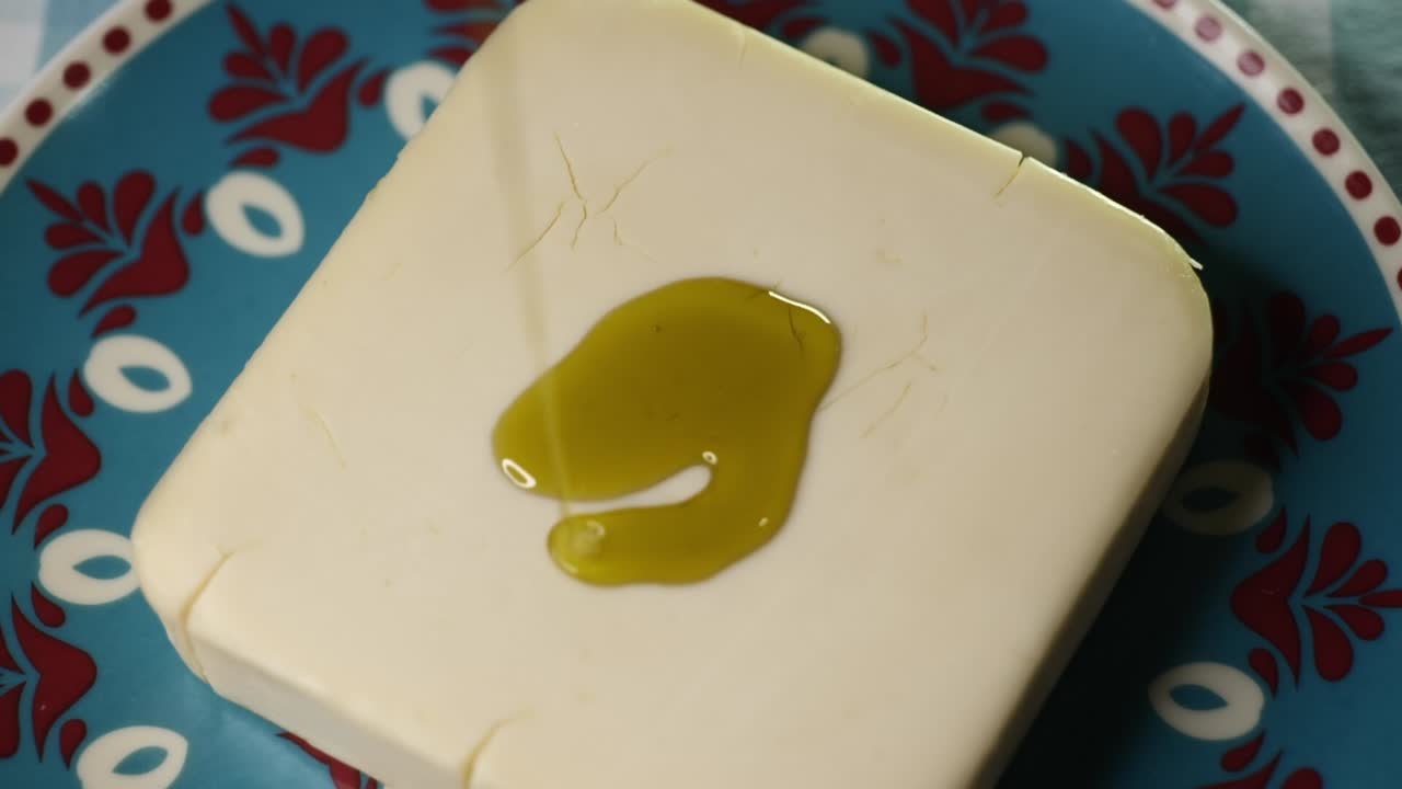 Pouring Extra Virgin Olive Oil (EVOO) over a piece of cheese in a traditional Andalusian dish