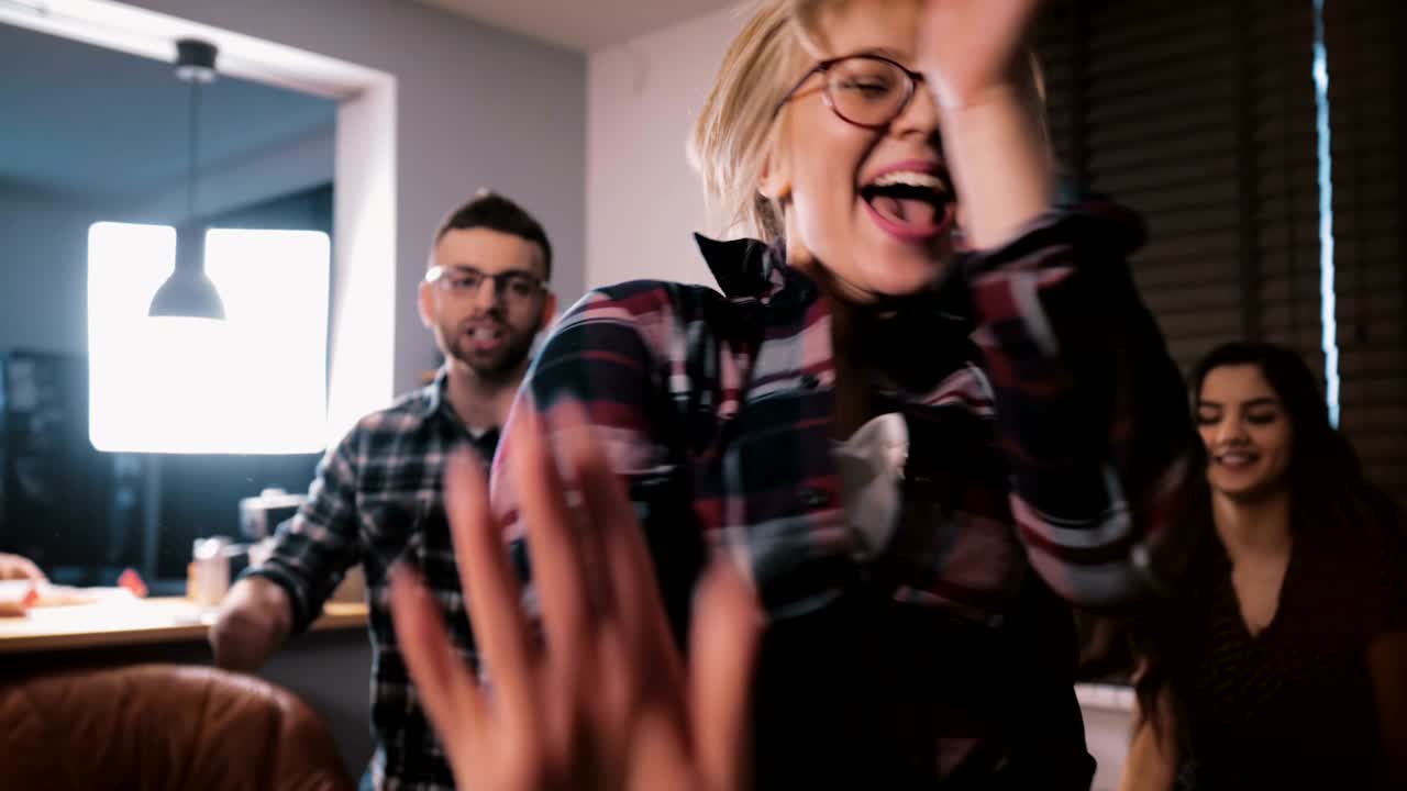 Successful young European female boss celebrating business achievement with multiethnic friends dancing slow motion