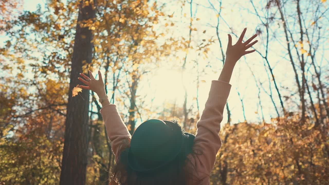 mujer disfrutando de las hojas de otoño en un bosque