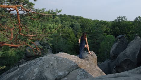 young female in blue dress on edge of a cliff. mystic pictures, ballet dancer stands on cliff end