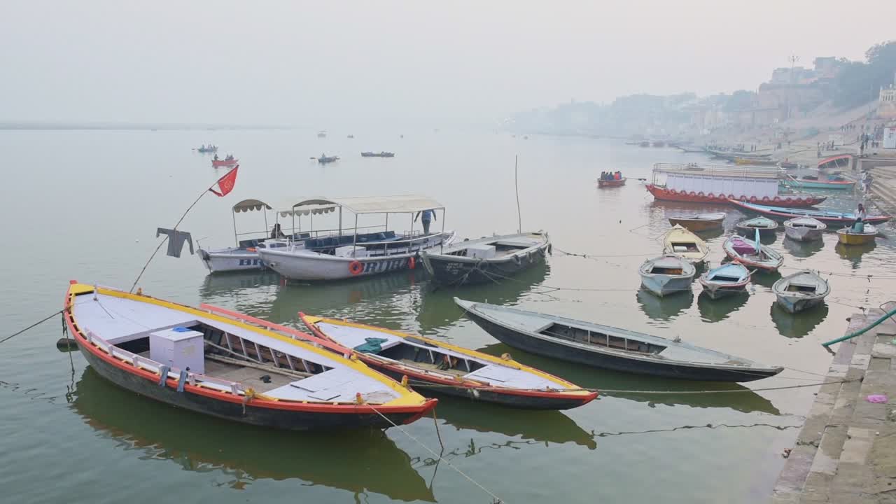 Small Boats Docked In The River Ganges Located In Varanasi, Uttar Pradesh, India. -medium shot
