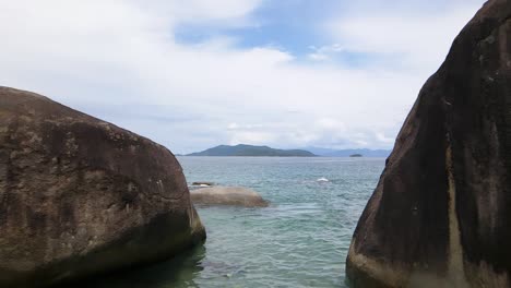 Entering-the-sea-between-rocks-in-Angra-dos-Reis,-Rio-de-Janeiro,-Brazil