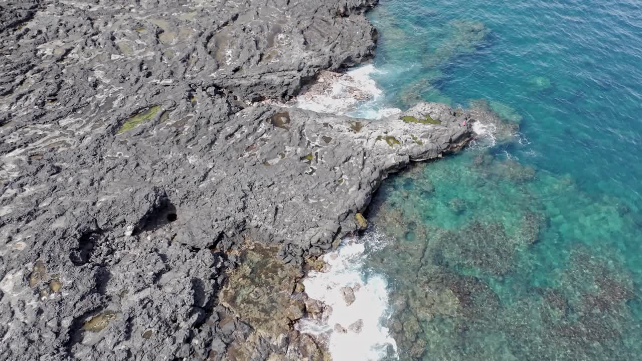 vista de avión no tripulado mirando hacia abajo, flotando sobre la costa rocosa de pointe au sel en saint-leu, isla de la reunión, con un movimiento lento hacia adelante