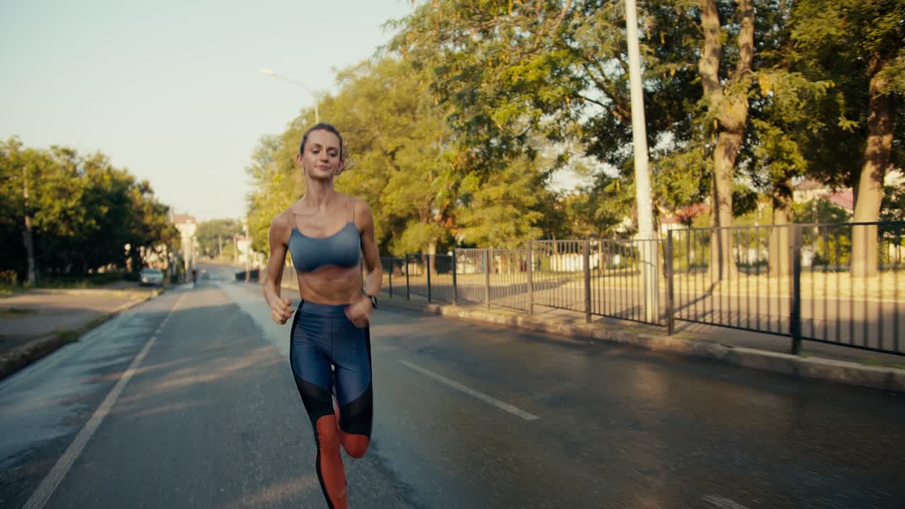 vista general de una chica en forma en un uniforme deportivo que está corriendo por la carretera por la mañana. deportes al aire libre